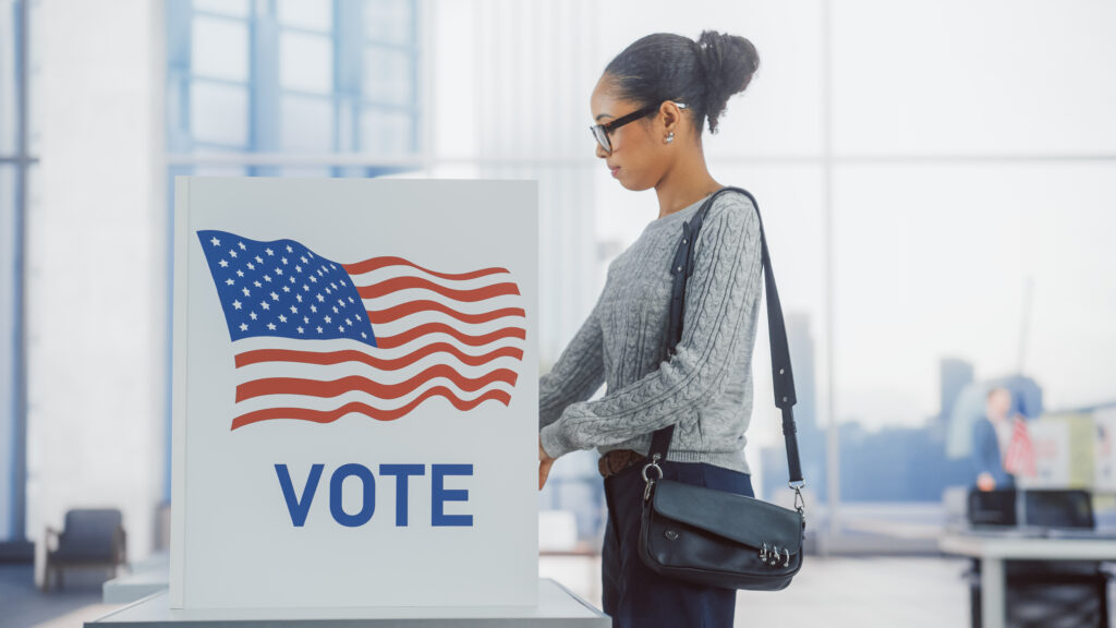 An African-American woman stands at a voting booth